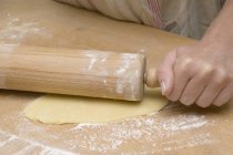 Closeup view of person rolling out dough — Stock Photo