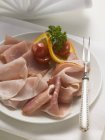 Sliced ham on plate with meat fork — Stock Photo