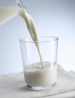Verter leche en un vaso - foto de stock