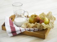 Vue rapprochée des pommes et du lait dans le plateau — Photo de stock