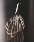 Closeup view of one metal whisk on reflective surface — Stock Photo
