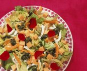 Closeup view of lettuce with peppers, mango and pesto on plate — Stock Photo