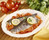 Closeup view of steamed trouts with tomatoes and lemons — Stock Photo