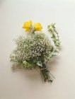 Closeup view of a bouquet of daffodils, gypsophila and ivy on a white surface — Stock Photo
