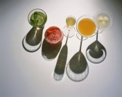 Vista dall'alto di varie bevande in bicchieri con ombre su superficie bianca — Foto stock