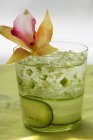 Refreshing cucumber drink with flower on green surface — Stock Photo