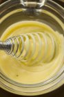 Closeup view of Hollandaise sauce with a whisk in glass bowl — Stock Photo