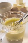 Hollandaise sauce with a whisk in a small glass pan — Stock Photo
