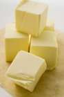 Closeup view of piled cubes of butter on wooden board — Stock Photo
