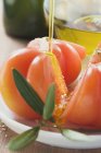 Verter aceite de oliva sobre los tomates - foto de stock