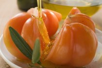 Verter aceite de oliva sobre los tomates - foto de stock