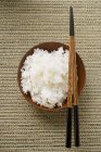 Bowl of rice and chopsticks — Stock Photo