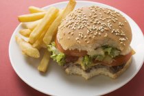 Bitten Cheeseburger with chips — Stock Photo