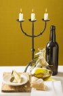 Nature morte avec olive, fromage parmesan, pain, huile, bouteille de vin et chandelier — Photo de stock