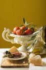 Natura morta con olive, salsiccia affettata, parmigiano, pane, olio e pomodori — Foto stock