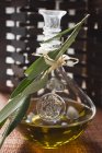 Closeup view of olive oil in carafe with olive branch — Stock Photo