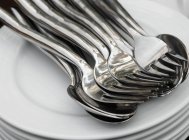Closeup view of piled plates with spoons and forks — Stock Photo