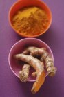 Roots and ground turmeric in bowls — Stock Photo