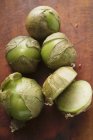 Several tomatillos, one cut open  over wooden surface — Stock Photo