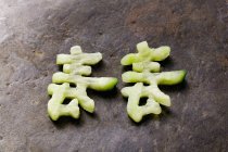 Chinesische Schriftzeichen aus Gurke über Holzoberfläche — Stockfoto