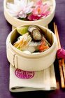 Steamed sea bass with ginger and vegetables in wooden bowl over towel — Stock Photo