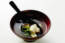 Miso soup in dark bowl on white surface — Stock Photo