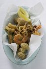 Top view of deep-fried seafood on paper and oval bowl — Stock Photo