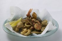 Closeup view of deep-fried seafood on paper and plate — Stock Photo