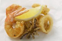 Vista de cerca de gambas fritas, pulpo, anillos de calamares y limón - foto de stock