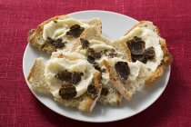 White bread with truffle spread  on white plate over red surface — Stock Photo