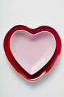 Closeup top view of red and pink heart-shaped plates on white surface — Stock Photo
