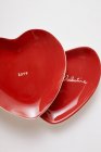 Closeup top view of red heart-shaped plates with the words Be my Valentine and Love — Stock Photo