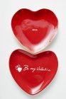 Closeup view of red heart-shaped plates with the words Be my Valentine and Love — Stock Photo