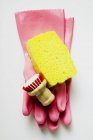 Gros plan vue de dessus des gants en caoutchouc rose avec éponge et brosse — Photo de stock