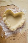 Closeup view of raw pastry in heart-shaped pie dish — Stock Photo