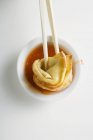 Closeup top view of dipping a deep-fried Wonton in sweet and sour sauce — Stock Photo