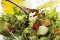 Verter aceite de oliva en ensalada - foto de stock