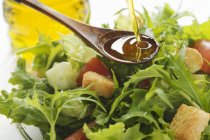 Pouring olive oil into salad — Stock Photo