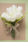Top view of white tulips tied in a bunch on a piece of paper — Stock Photo