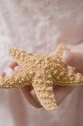 Closeup cropped view of girl holding starfish — Stock Photo