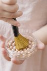 Primo piano vista ritagliata di ragazza in possesso di perle di polvere e pennello — Foto stock