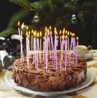 Vista de cerca de pastel de chocolate con velas encendidas - foto de stock