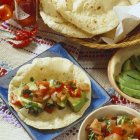 Tortilla mit Avocado und Tomatenfüllung auf blauem Teller — Stockfoto