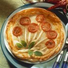 Closeup view of pie decorated with tomato slices and sage — Stock Photo