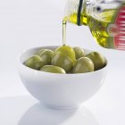 Verter aceite de oliva sobre las aceitunas - foto de stock