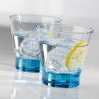 Closeup view of two glasses of water with ice cubes and a slice of lemon — Stock Photo