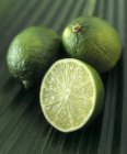 Limes entières et coupées en deux — Photo de stock