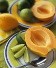 Halved papaya with lime wedges — Stock Photo