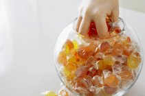 Vista ritagliata di caramelle afferrando a mano dal barattolo dolce — Foto stock