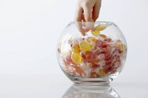 Primo piano vista ritagliata di mano prendendo caramelle da vaso di vetro — Foto stock